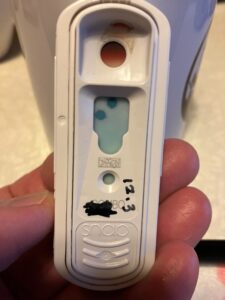 手に持った猫用エイズ・白血病検査キット。判定窓に陽性を示す2つの青いドットが見える